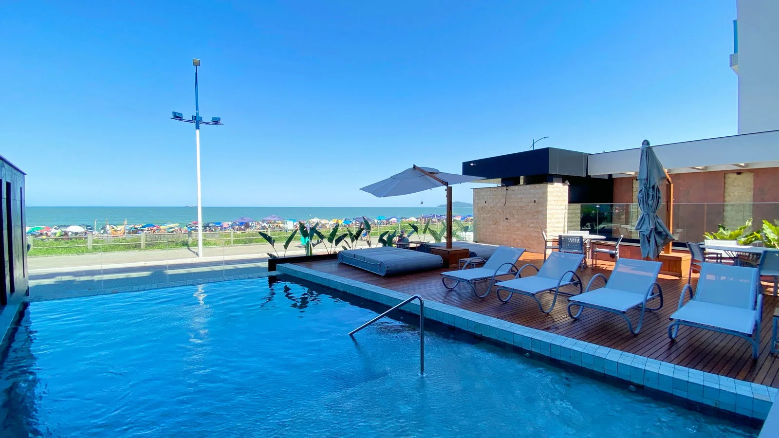 Piscina do Bay House com espreguiçadeiras e vista para a Praia Brava