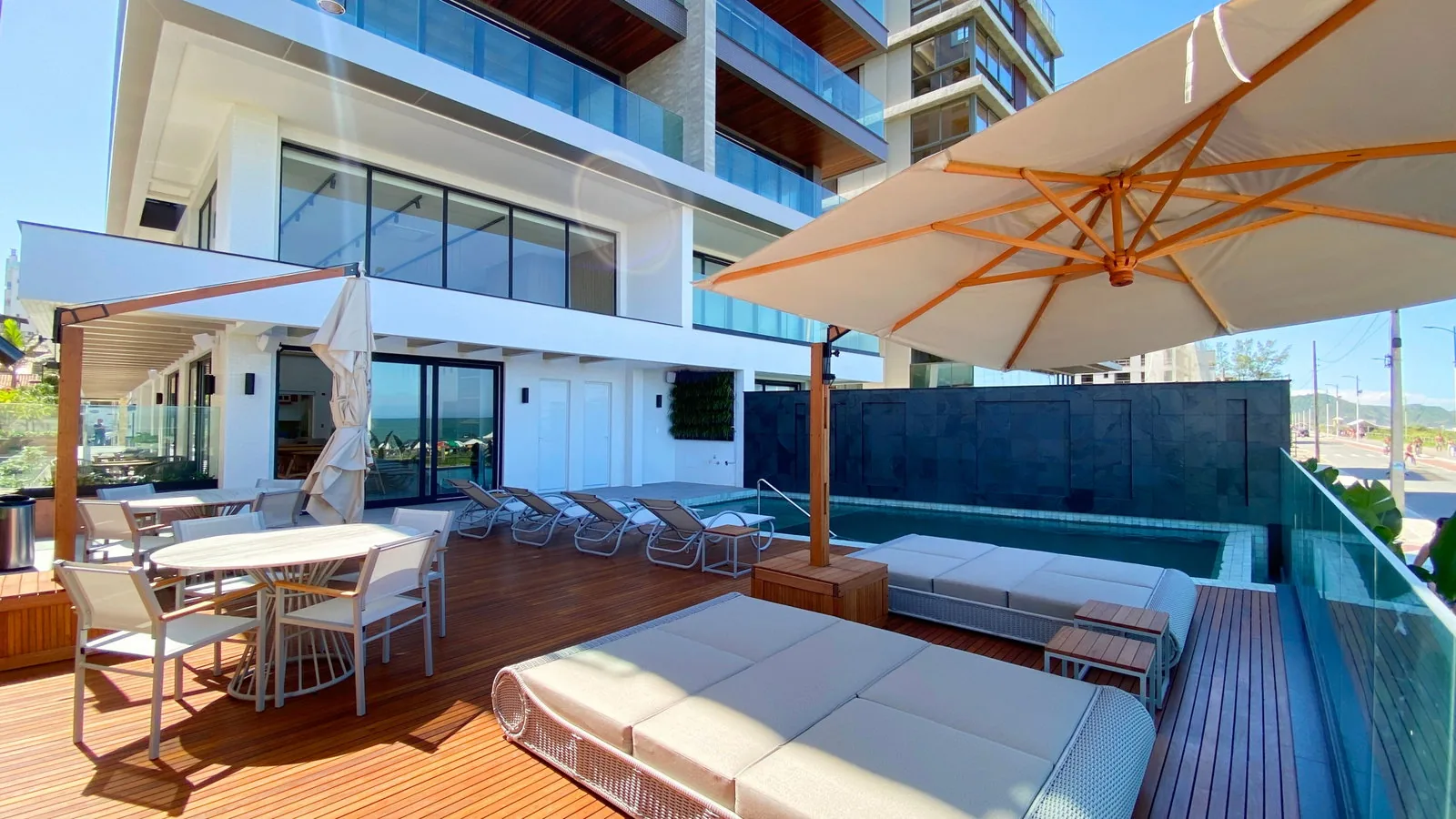 Deck da piscina do Bay House com ombrelones e área de convívio