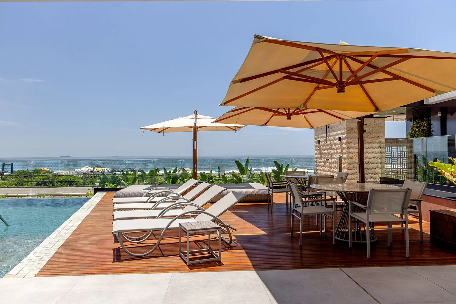 Área externa do Bay House com piscina e vista para o mar
