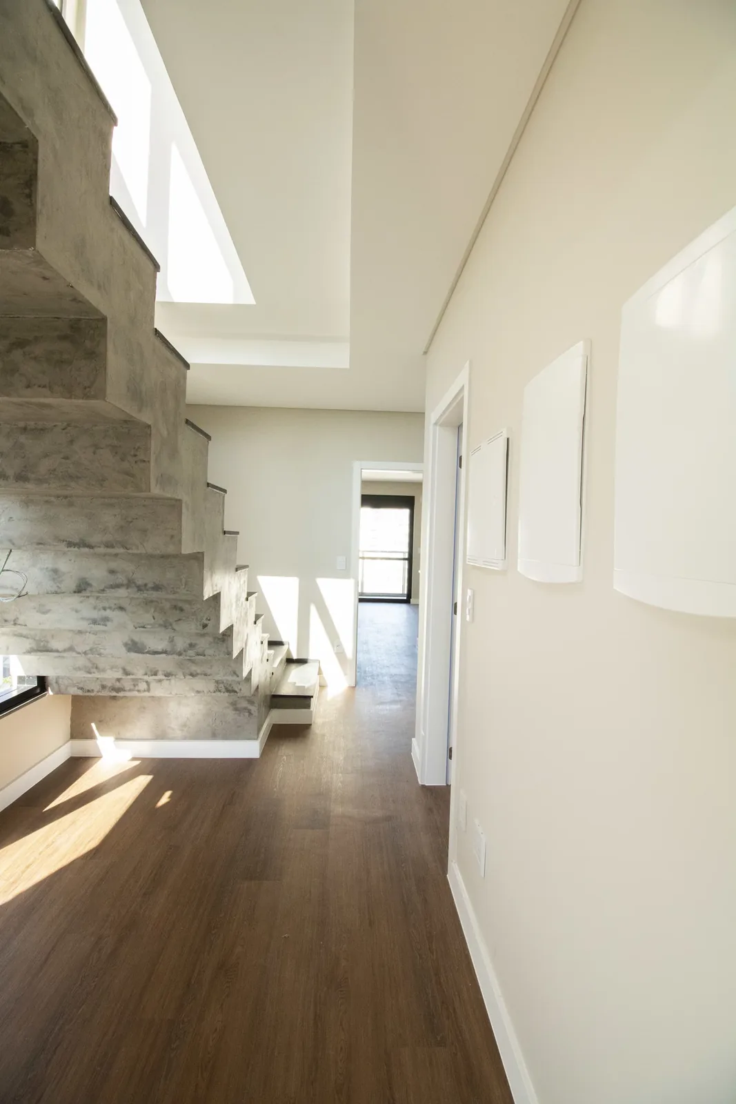 Hall do duplex do Brava 22, com parede em pedra e escada interna