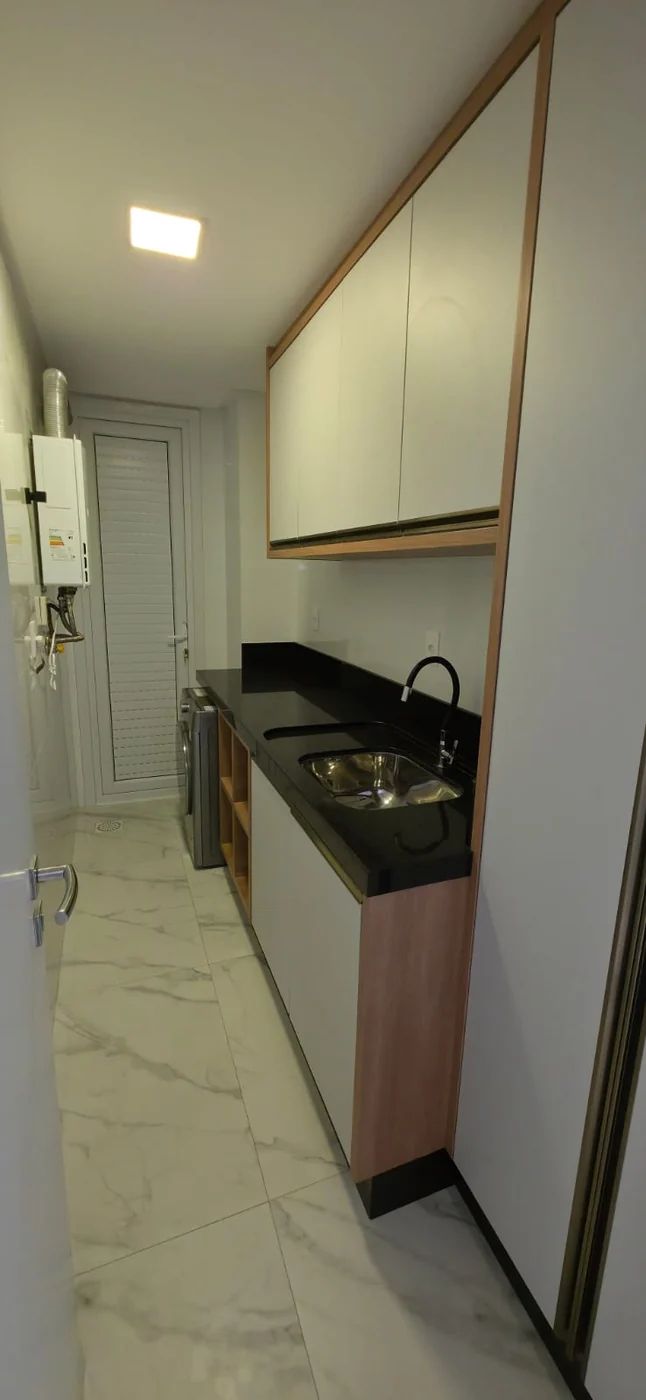 Área de serviço do apartamento do Brava Prime, com armários, tanque e aquecedor a gás