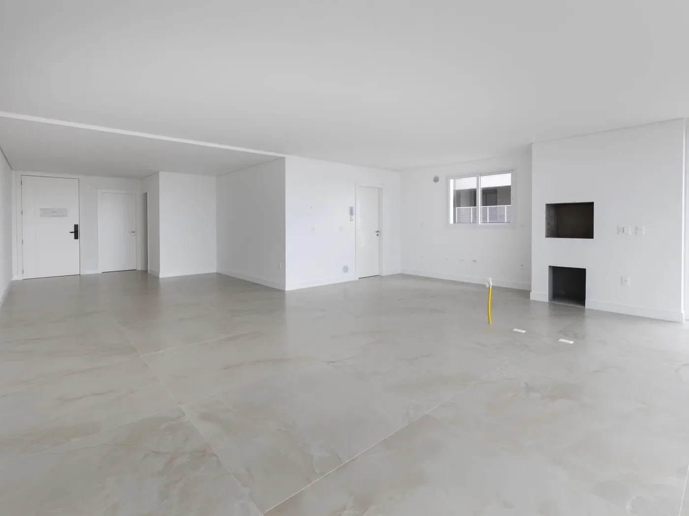 Sala do apartamento 501 do Le Blanc, com painel de TV e porcelanato