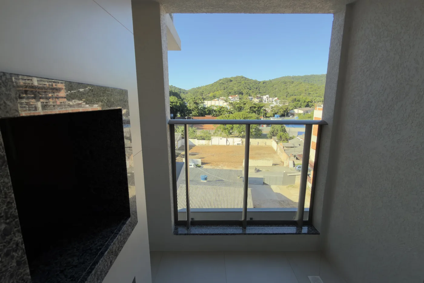 Sacada do apartamento do Soul Brava Club, com churrasqueira e vista para o morro da Praia Brava