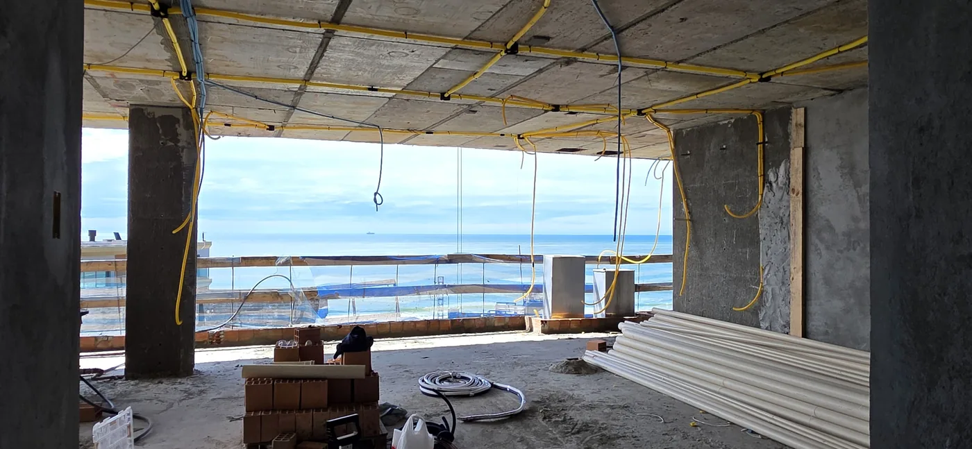 Living do apartamento com abertura para o mar, em obra